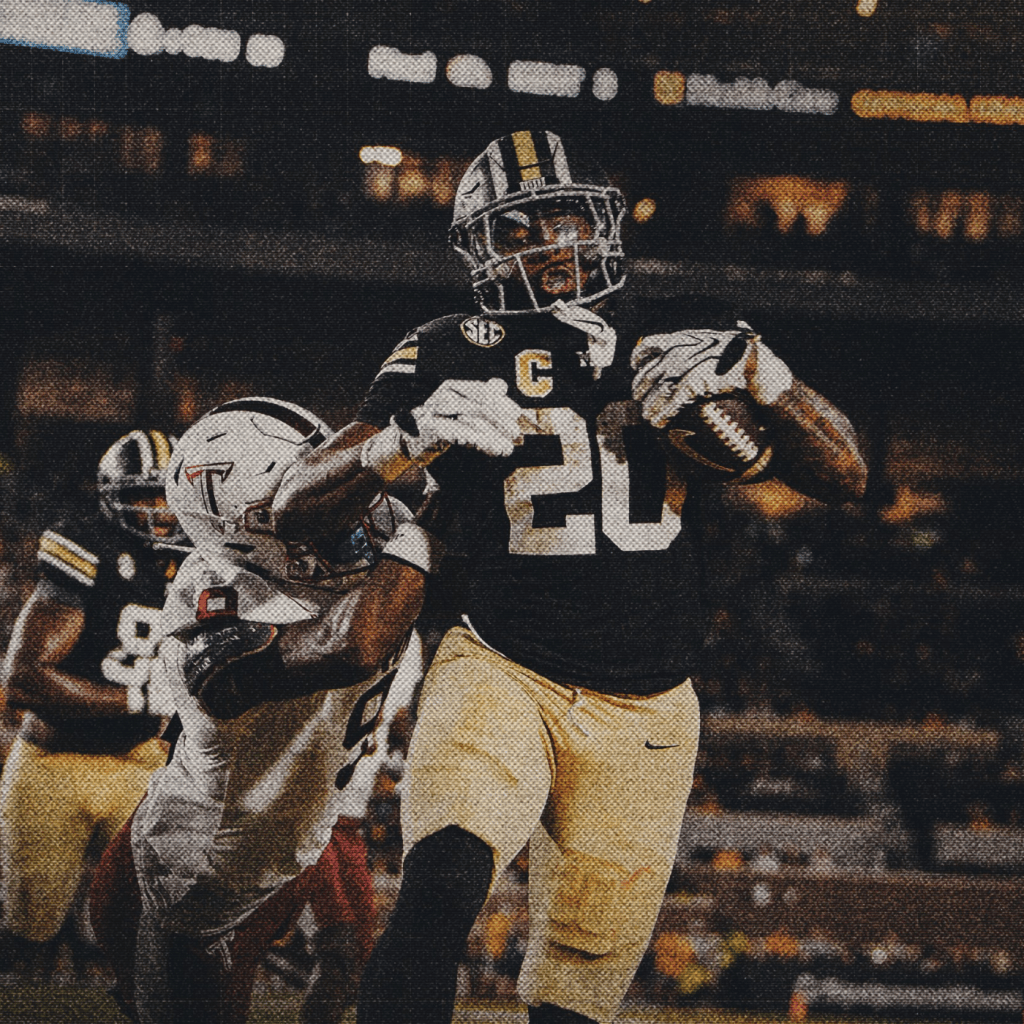 Missouri running back Jamal Roberts, number 20, in a black jersey with a captain's patch and gold pants, stiff-arms a Troy defender while carrying the football during a night game.